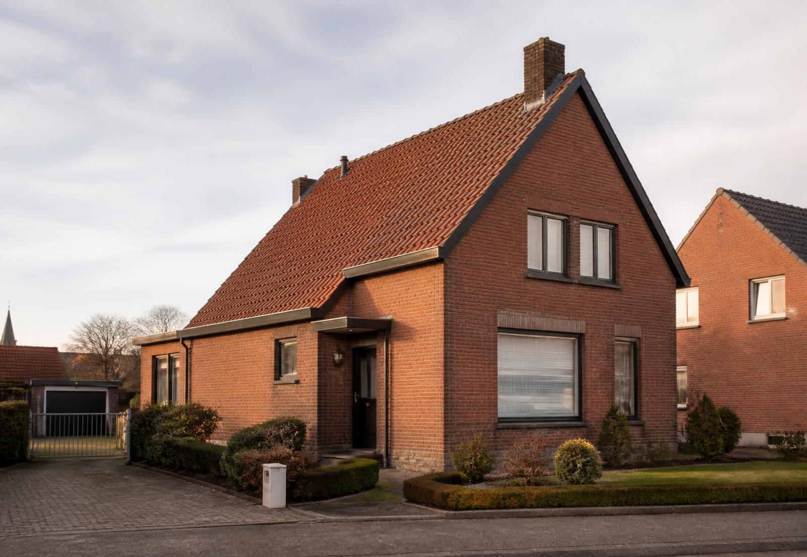 Vlaamse woning met bakstenen gevel en pannendak in een residentiële straat